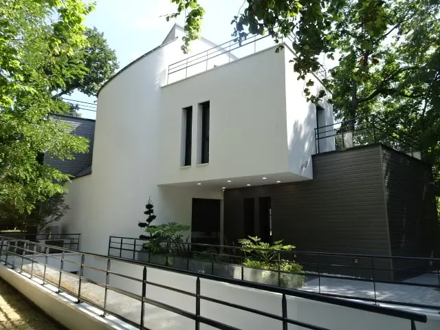 La façade blanche et grise avec rampe et garde-corps devant les ouvertures du rez-de-chaussée — chantier au Vésinet.