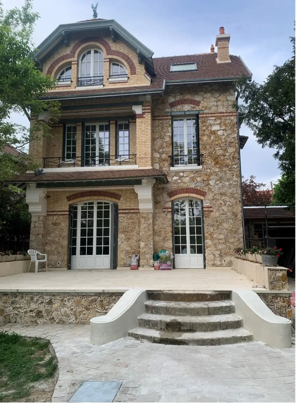 La maison en pierre et brique avec menuiseries claires, terrasse et escalier donnant sur le jardin — chantier à Taverny.